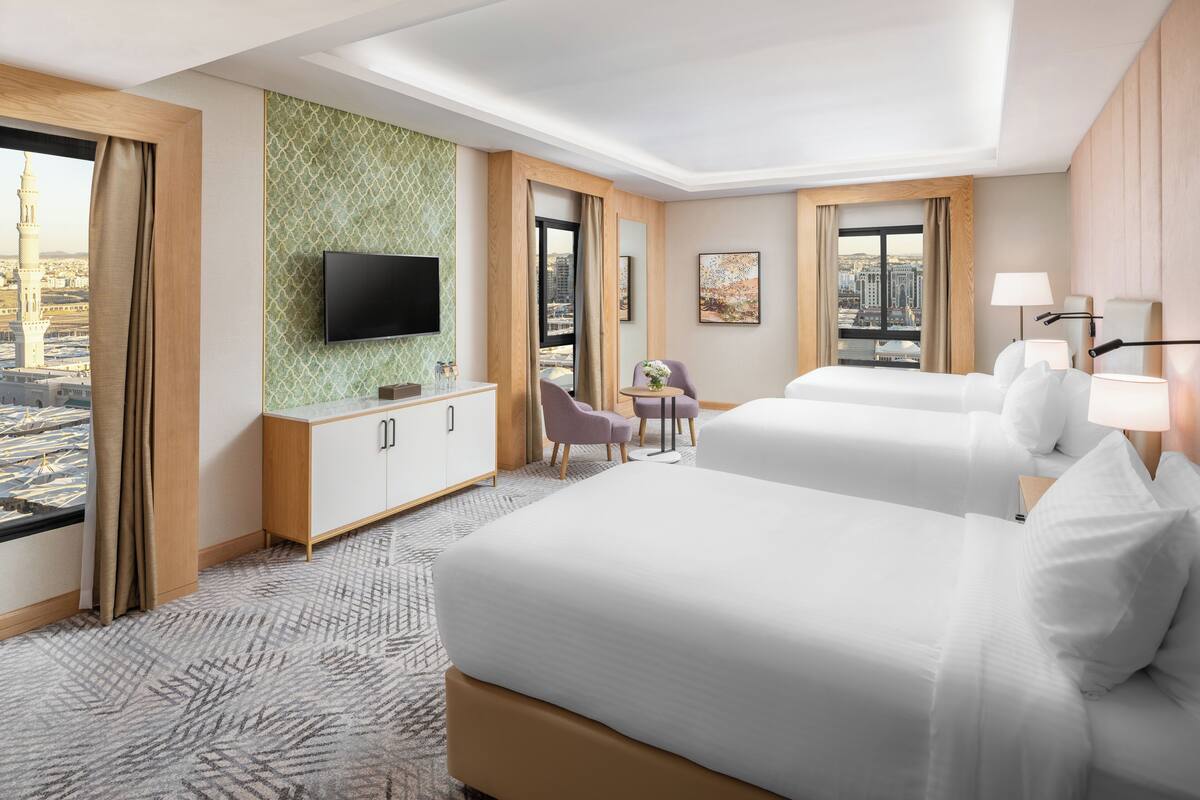 Een hotelkamer met twee bedden, een televisie, een bureau en uitzicht op de stad.