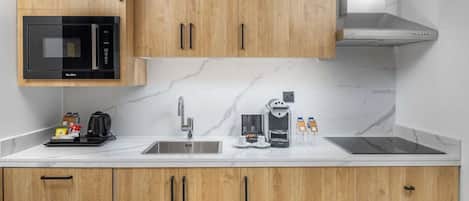 Una cocina moderna con armarios de madera, microondas integrado, cafetera y extractor de acero inoxidable.