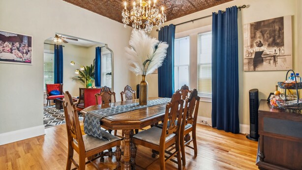 A dining area with a wooden table, chairs, a chandelier, and a decorative vase with white feathers. - Happy Shack Ybor City-Historic District-Steps to 7th Ave (Tampa)