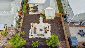 An aerial view of a residential area with a central house featuring a fenced backyard with a patio and garden. - Happy Shack Ybor City-Historic District-Steps to 7th Ave (Tampa)