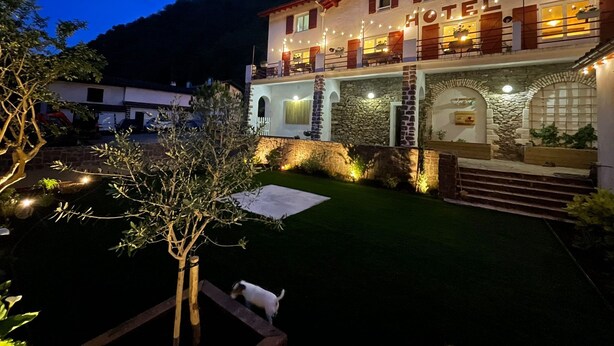 A hotel with a stone facade, a balcony with outdoor seating, and a well-lit entrance. - Clementenia (Arneguy)