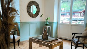 A room with a wooden floor, a round mirror, a small table with a vase, and a chair. - Clementenia (Arneguy)