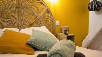 Una cama con cabecera trenzada, una mesita de noche con lámpara y una lámpara de pared.