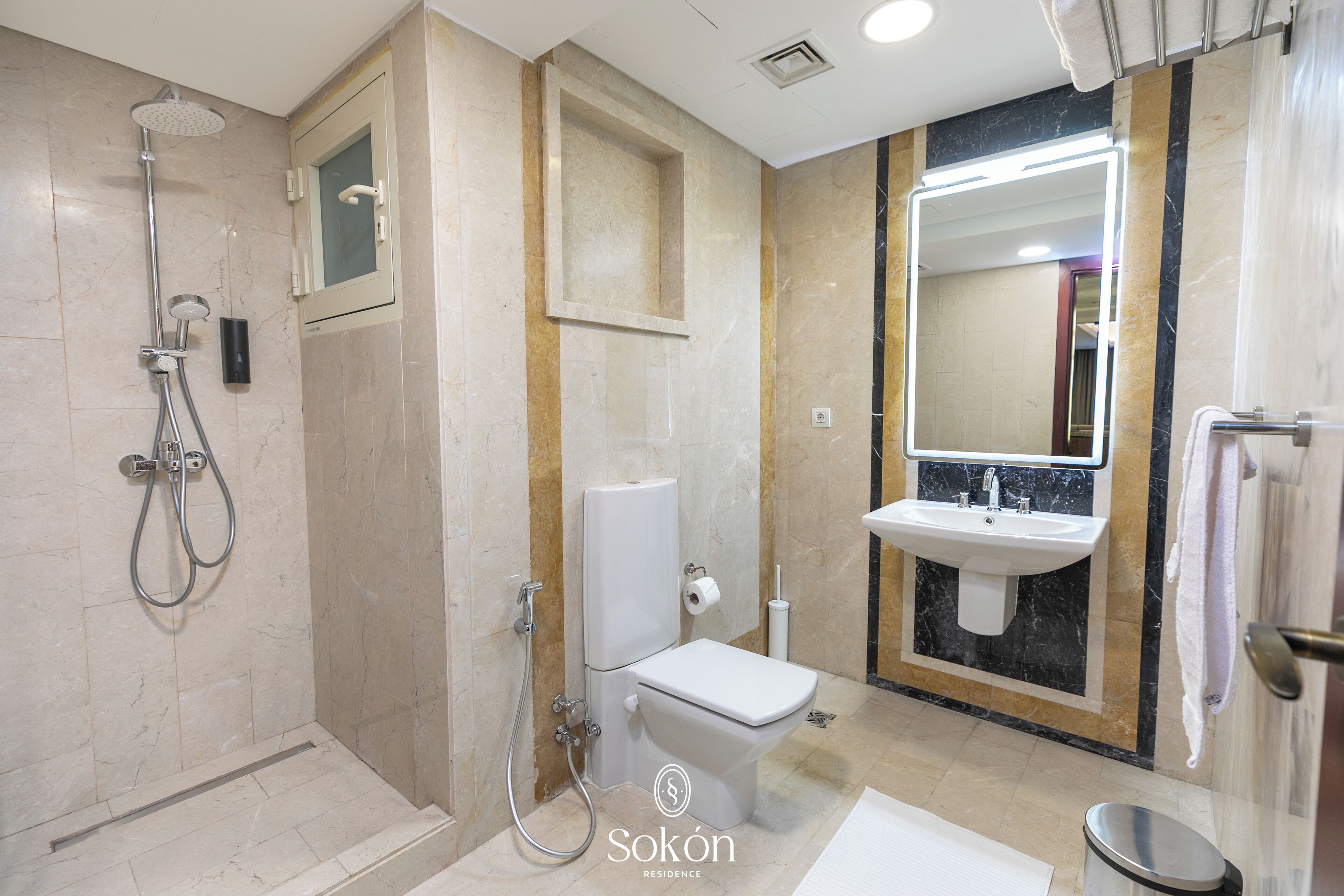 Un baño moderno con ducha, inodoro, lavamanos y un espejo grande.