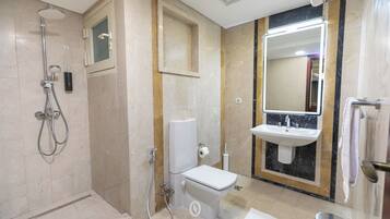 Un baño moderno con ducha, inodoro, lavamanos y un espejo grande.