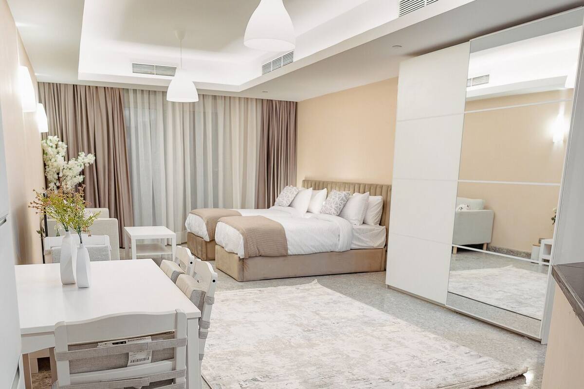 A modern hotel room with a bed, bedside table, and a large mirror.