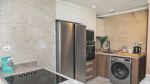 A modern kitchen with a built-in oven, a stainless steel refrigerator, a washing machine, and a sink. - Sokon Residence Nile View at Hilton (Cairo)