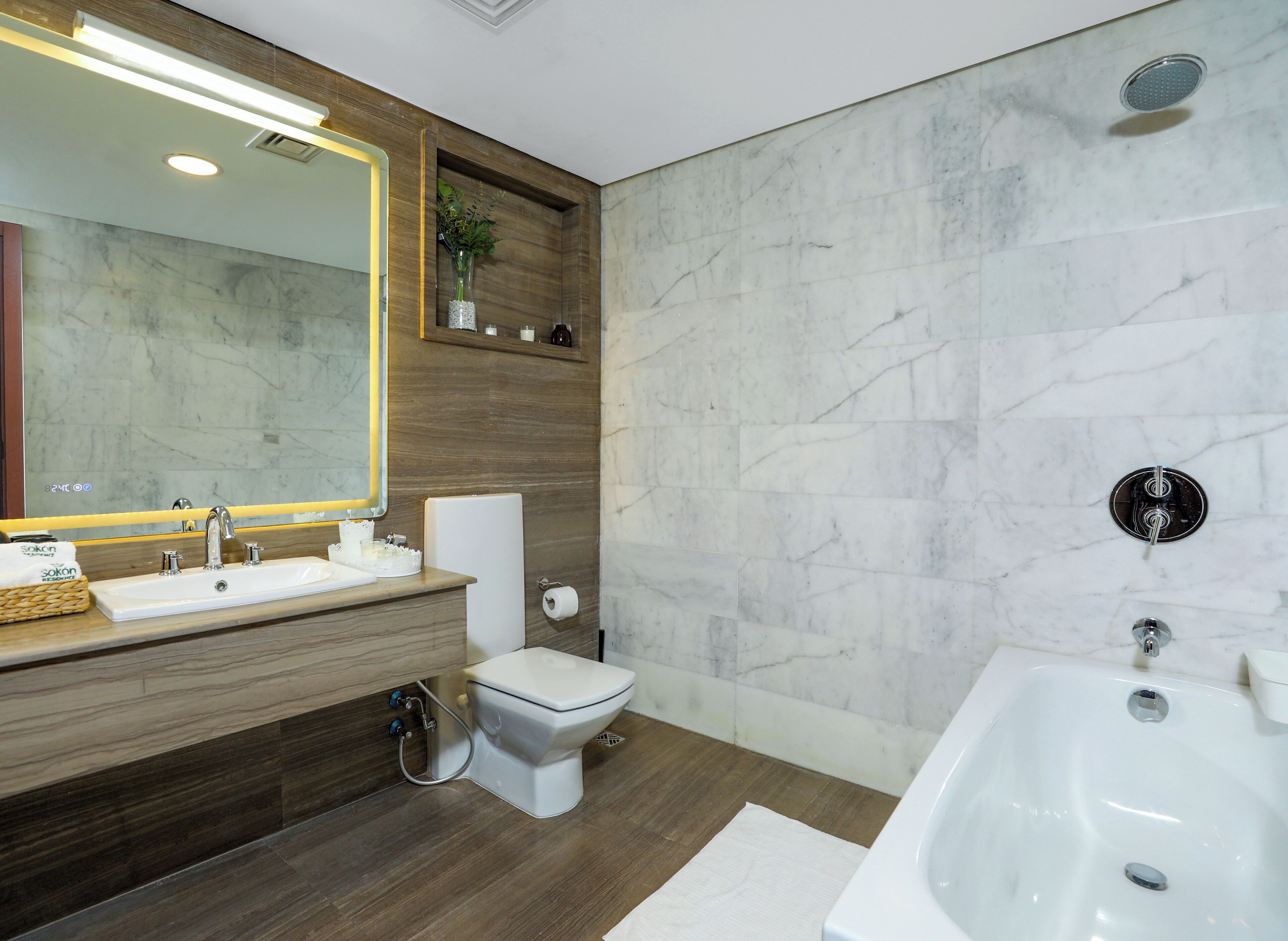 A modern bathroom with a large mirror, a sink, toilet, and a bathtub.