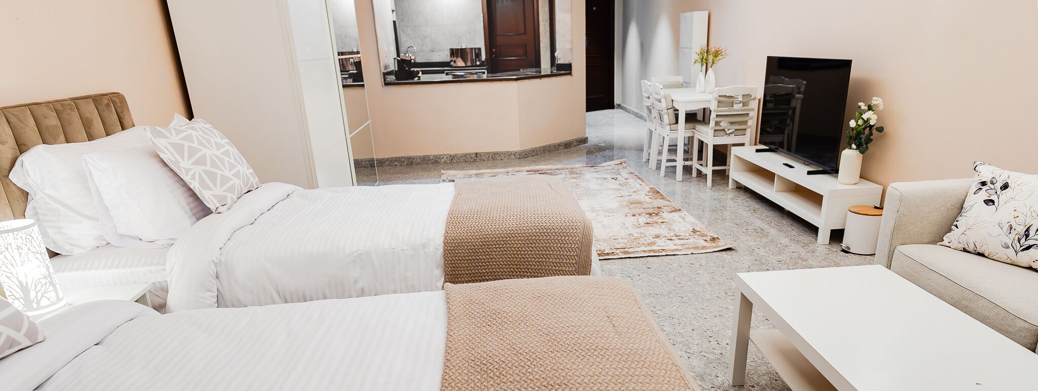 Een moderne hotelkamer met een bed, een bank, een televisie en een klein zithoekje.
