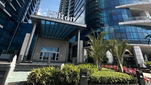 A modern hotel with a curved glass facade and the name 'Hilton' prominently displayed. - Sokon Residence Nile View at Hilton (Cairo)