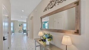 A hallway with a large mirror, a console table with lamps, and a potted plant.