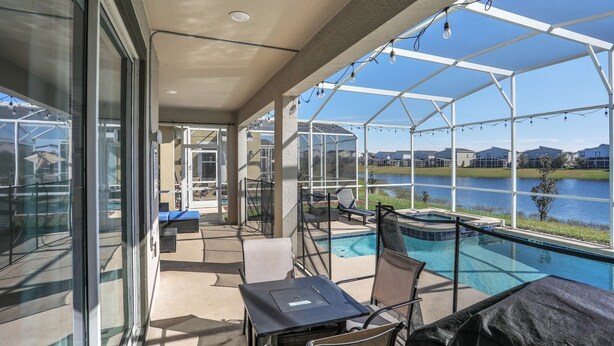 A covered outdoor area with a pool, lounge chairs, and a table.
