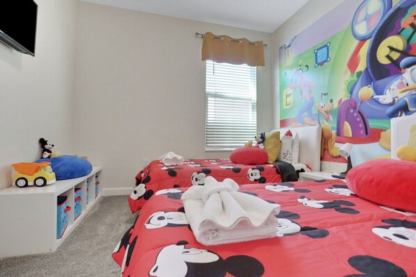A child's bedroom with a Mickey Mouse themed bedspread, a window with blinds, and a colorful mural on the wall. - 8966ccd-the Retreat At Championsgate 6 Bedroom Home (Davenport)