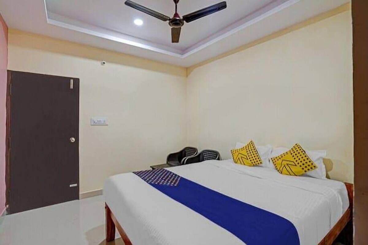 Une chambre d’hôtel avec un lit, un ventilateur de plafond, un bureau et une chaise.