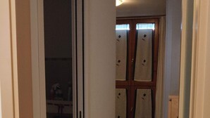 A narrow hallway with a bed and a wardrobe in the background.