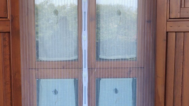 A wooden door with a mesh screen, leading to a tiled patio area.