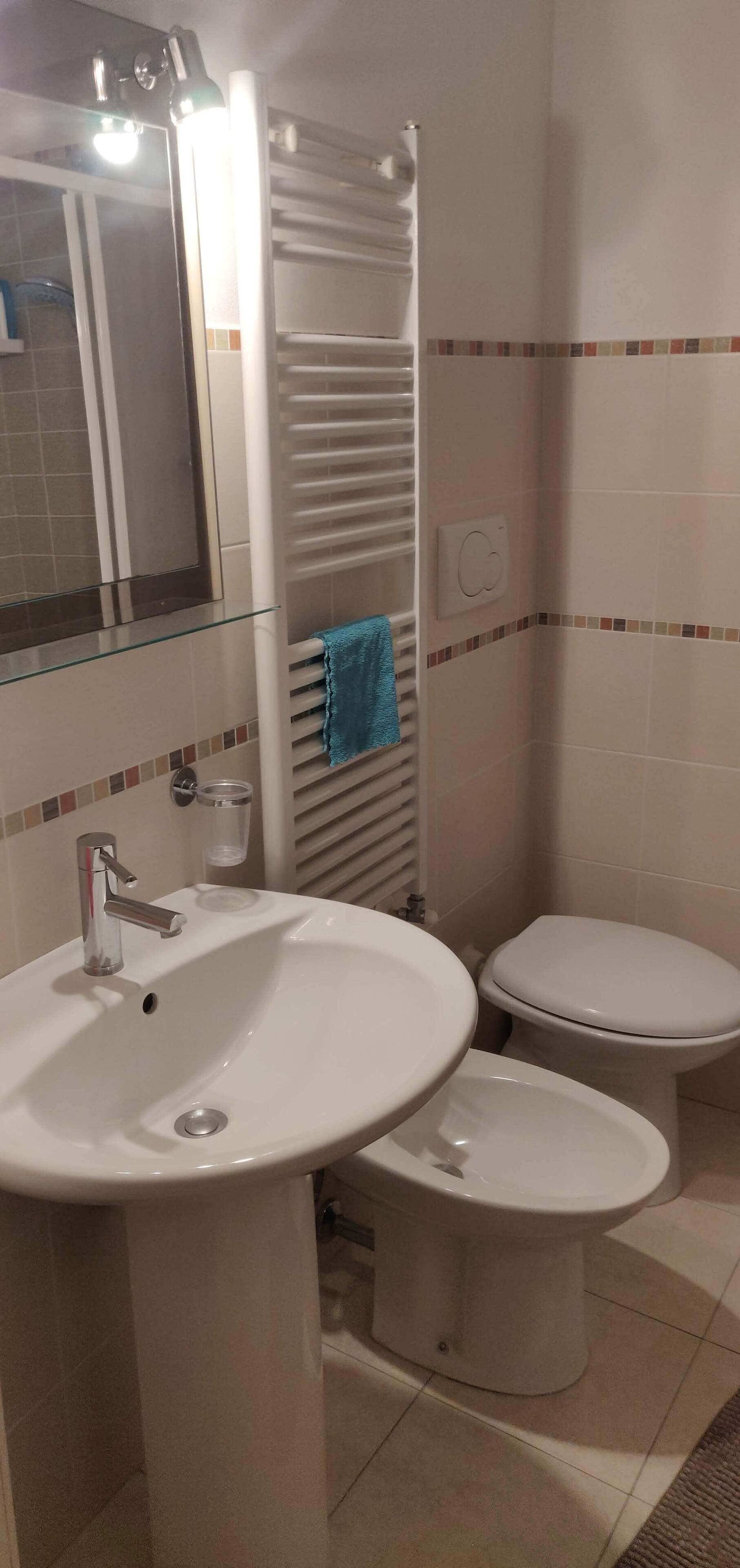 Un bagno con lavandino, wc e specchio.