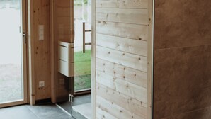 Interior de fusta amb una porta corredissa que dona a un balcó, un cap de cérvol penjat a la paret i un petit armari blanc.