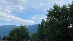 Un pont de fusta que s'estén sobre una massa d'aigua, envoltat de vegetació exuberant i muntanyes al fons.
