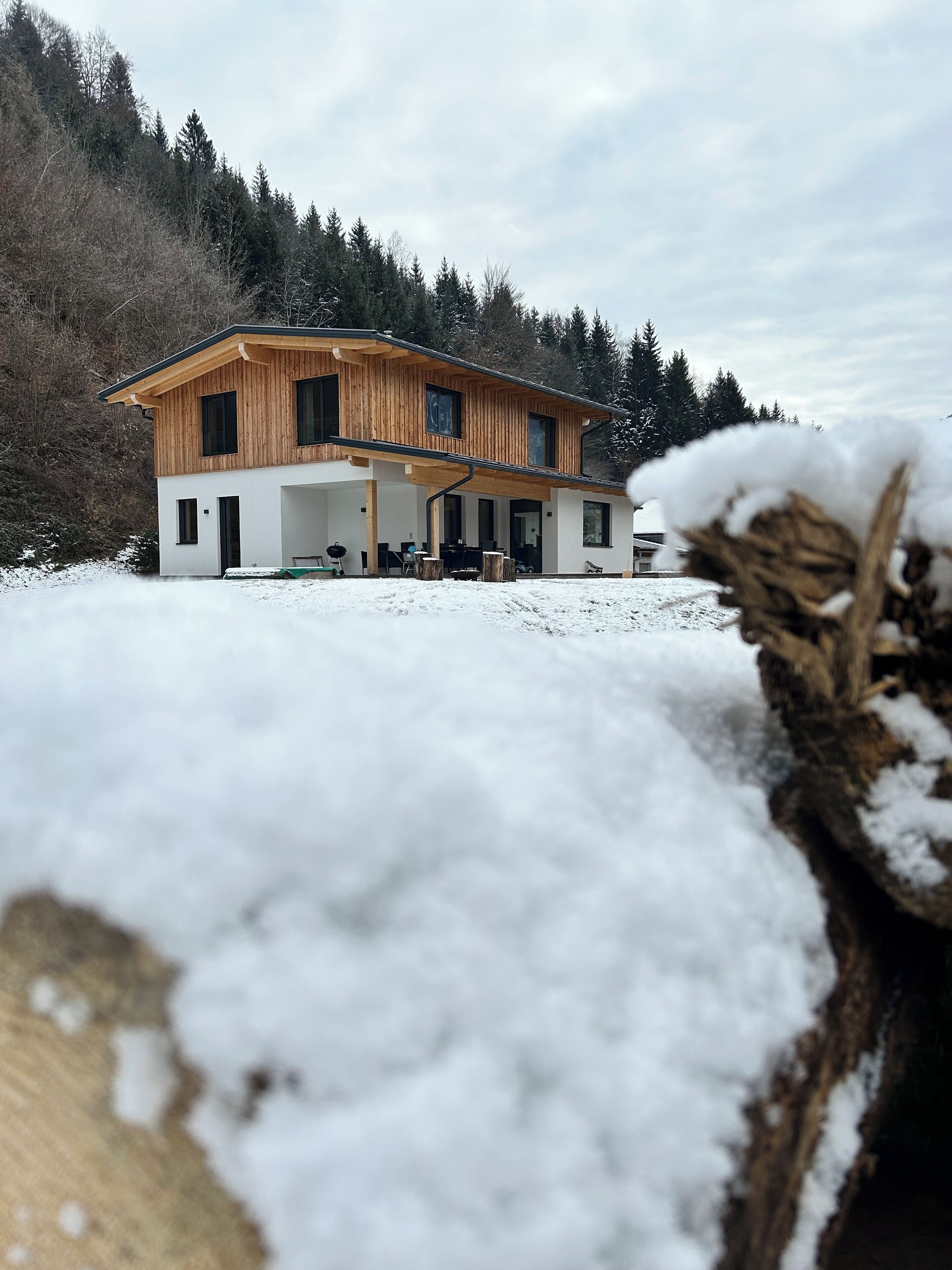 Una casa moderna de madera de dos pisos con un porche cubierto.