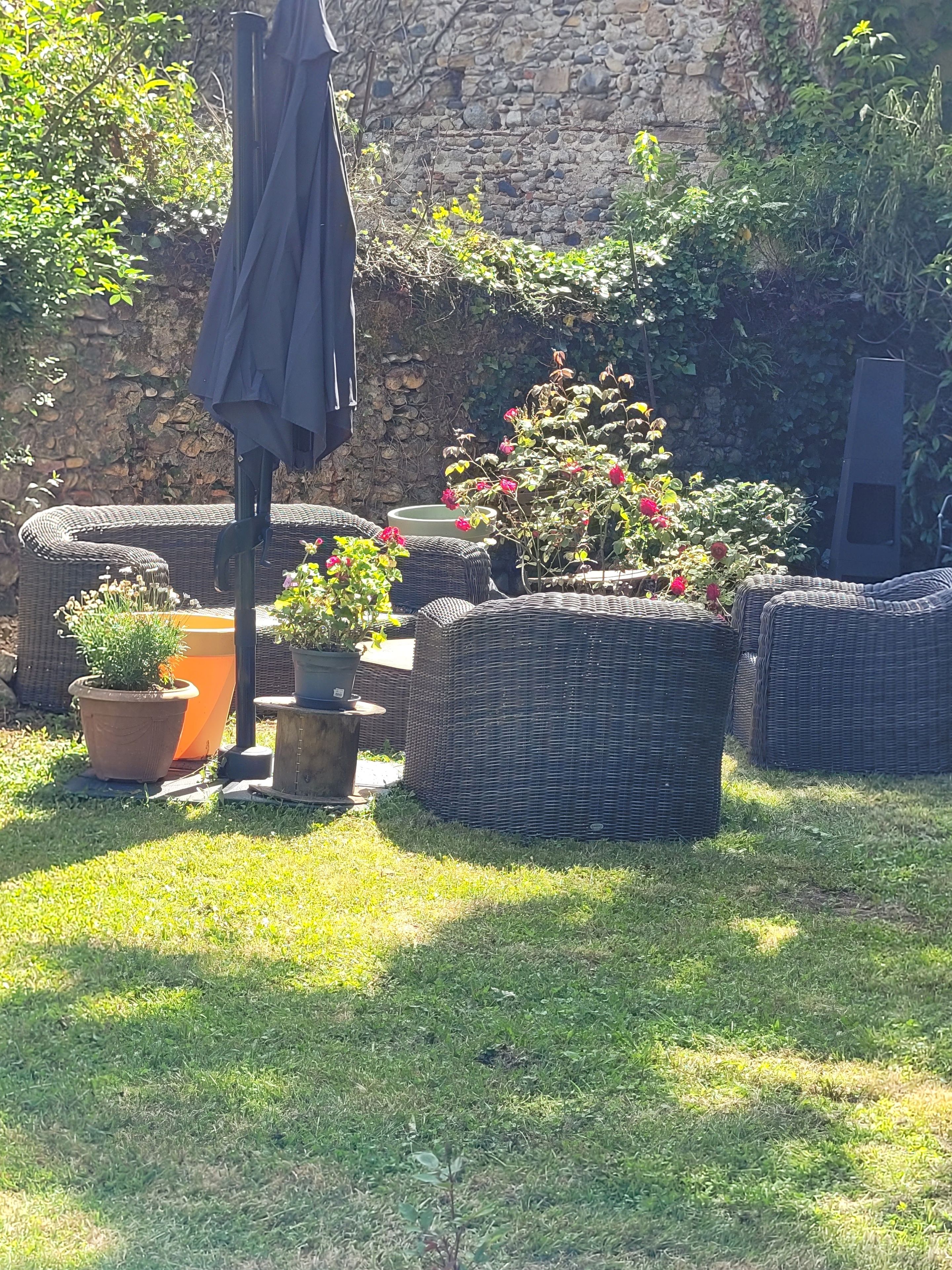 A garden area with wicker furniture, potted plants, and a stone wall.