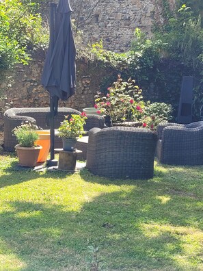 A garden area with wicker furniture, potted plants, and a stone wall.