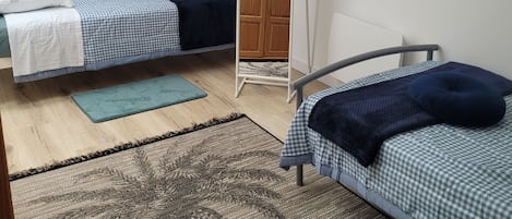 A bedroom with two single beds, a wardrobe, a mirror, and a chair.