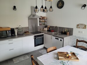 Eine moderne Küche mit Einbauofen, Mikrowelle und Spüle. Ein Esstisch mit Untersetzer und einer Schale mit Honiggläsern.