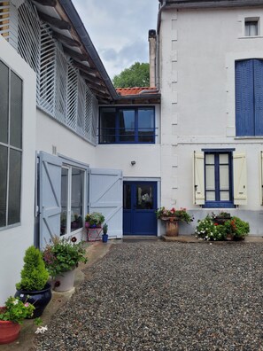 Ein Innenhof mit Kiesboden, einer blauen Tür und Topfpflanzen.
