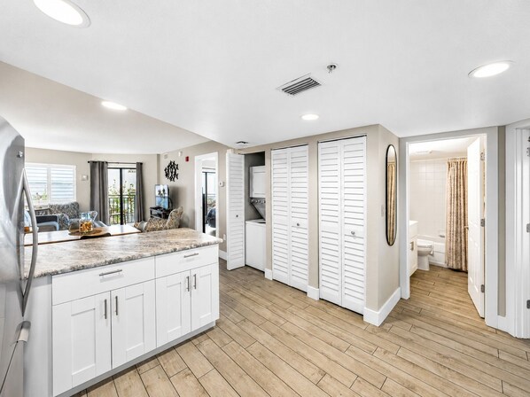 A modern kitchen with white cabinets, a marble countertop, and a built-in oven.