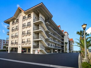 Ein mehrstöckiges Hotel mit Balkonen, einer Tiefgarage und blauem Himmel.