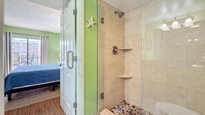 Ein Zimmer mit einem Bett, einer Duschkabine mit Glastür und einem Balkon mit Blick.