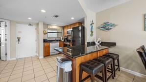 Una cocina moderna con una isla central, taburetes de bar, lavavajillas y refrigerador.