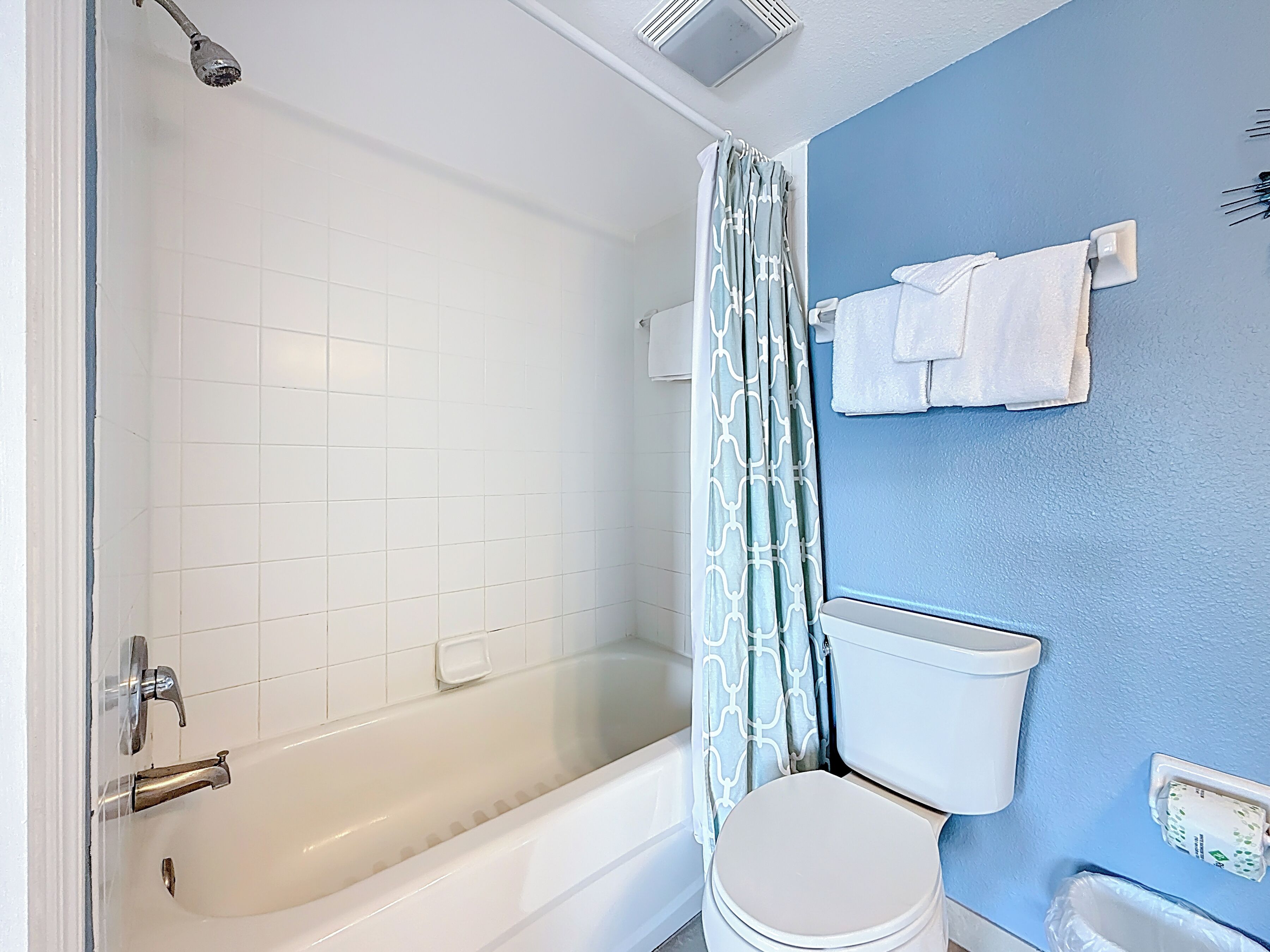 Un baño con bañera, inodoro y cortina de ducha.