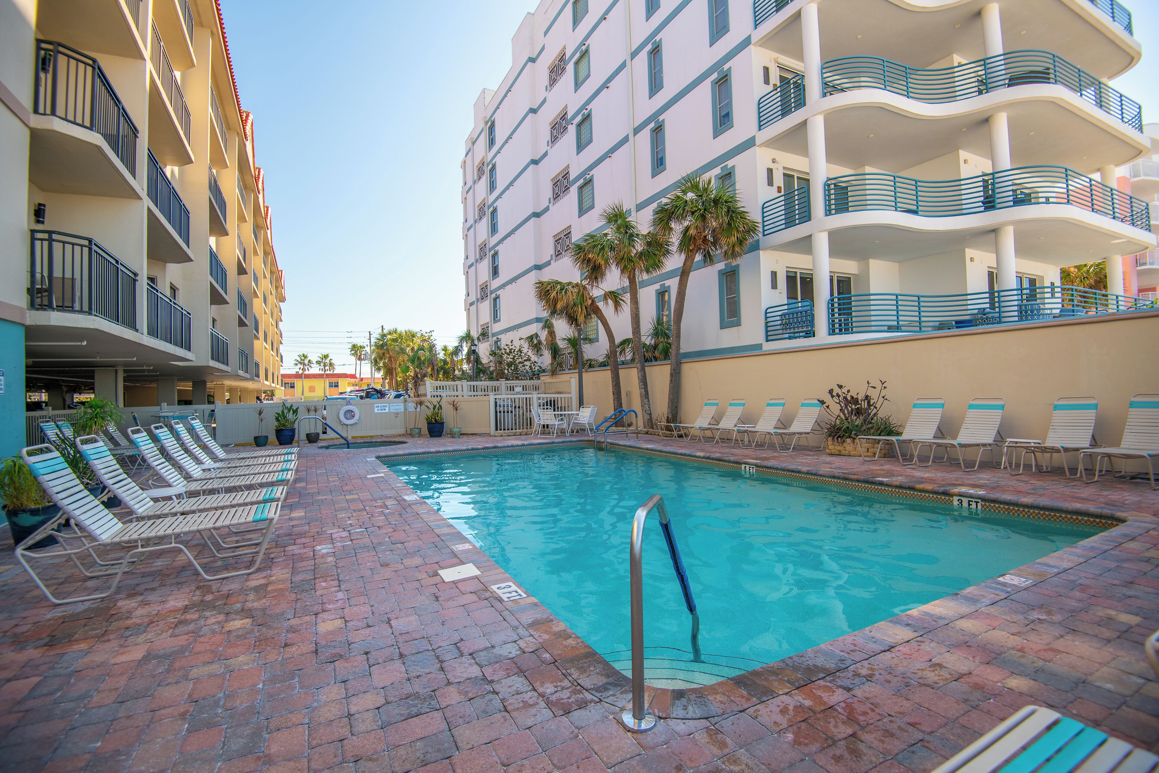 A swimming pool with lounge chairs, a poolside bar, and a building with balconies.
