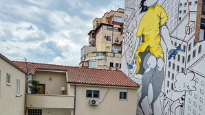 A building with a mural, multiple balconies, and a red-tiled roof. - Capital Inn Tirana (Tirana)