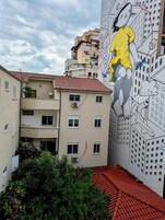 Un edificio con un mural, varios balcones y un tejado de tejas rojas.