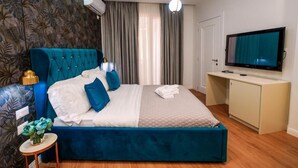 A bedroom with a large bed, a television, a desk, and a wall-mounted air conditioner. - Capital Inn Tirana (Tirana)
