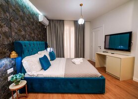 Un dormitorio con una cama grande, televisión, escritorio y aire acondicionado instalado en la pared.