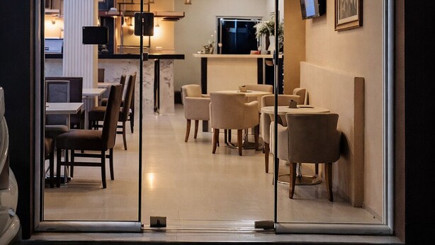 A modern interior with a curved ceiling, glass doors, and a seating area with tables and chairs. - Capital Inn Tirana (Tirana)