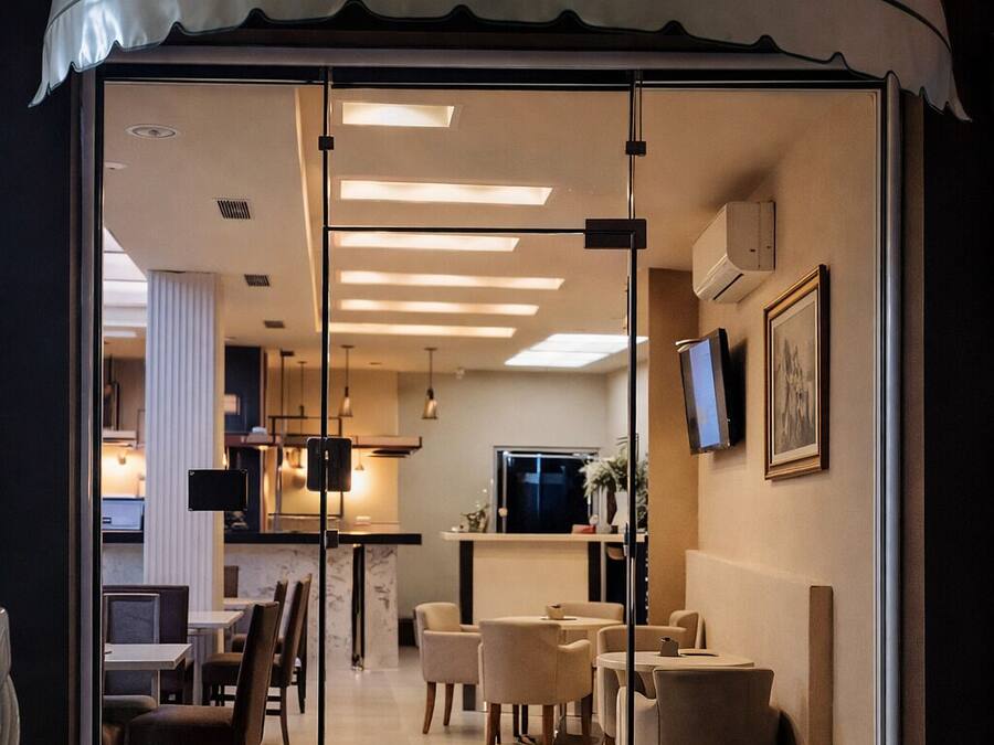A modern interior with a curved ceiling, glass doors, and a seating area with tables and chairs.