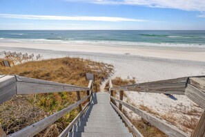 A wooden staircase leading to a beach with a clear view of the ocean.