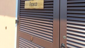 A door with horizontal slats and a wooden sign that reads "Iseo". - "Iseo" room (Marone)