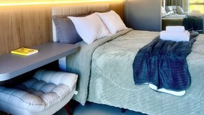 A modern hotel room with a bed, bedside table, and a seating area.