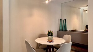 A dining area with a round table, four chairs, a vase with flowers, and a book.