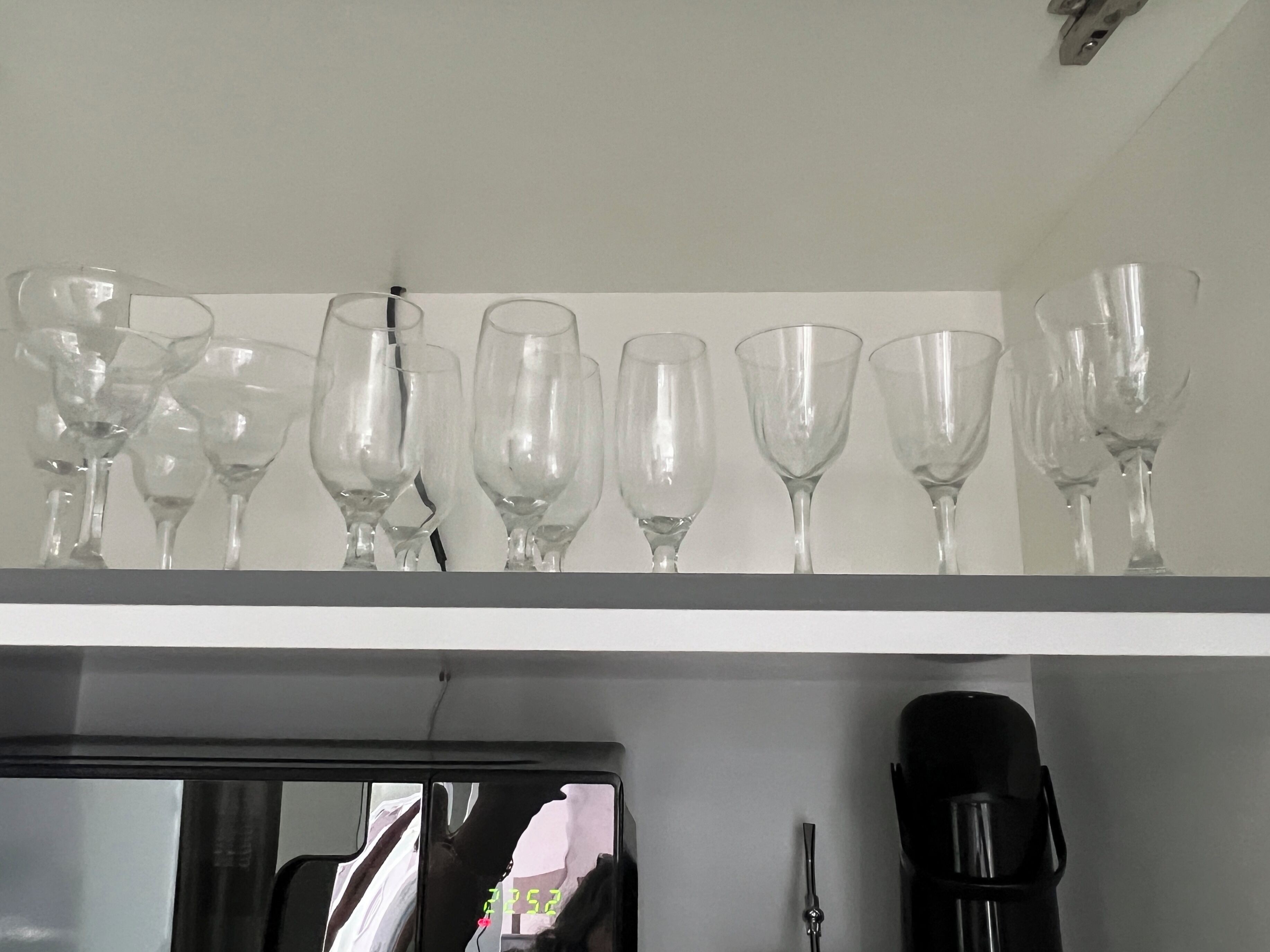Une étagère avec différents types de verres à vin et une machine à café.