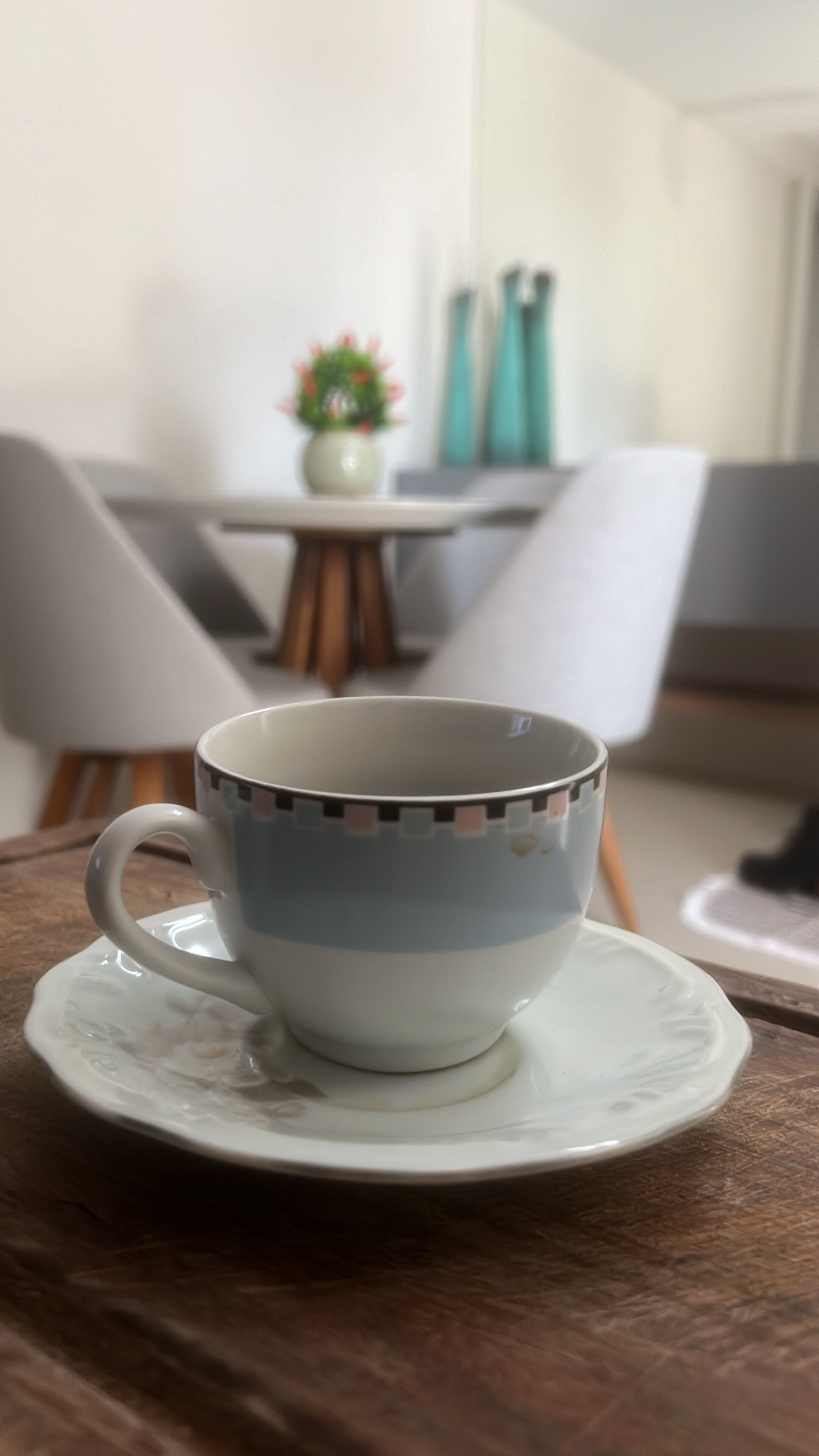 Uma xícara sobre um pires em uma mesa de madeira.