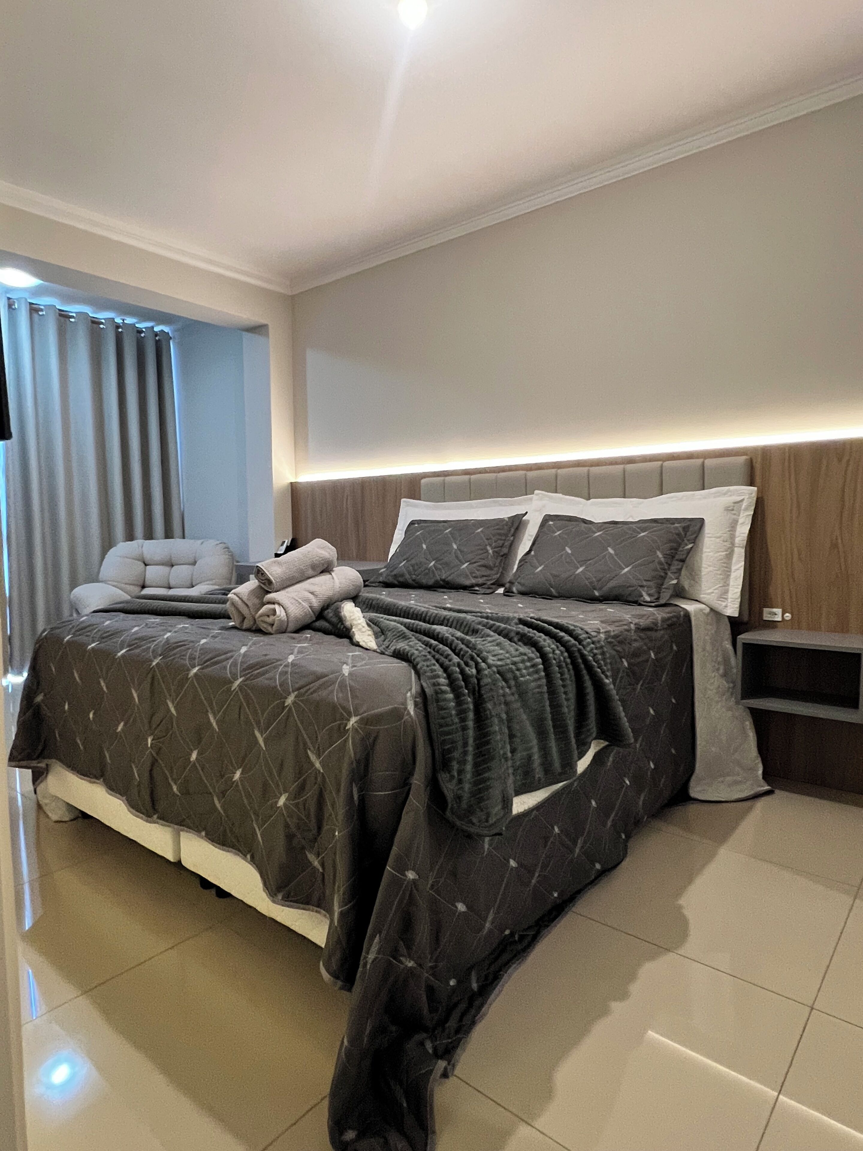 A modern bedroom with a large bed, a bedside table, and a headboard.