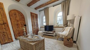 Ein gemütliches Wohnzimmer mit einem Holztisch, einem Fernseher und einem bequemen Sessel.