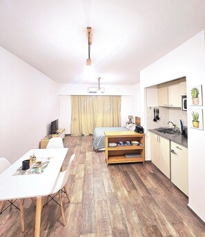A compact living space with a dining area, a bed, a kitchenette, and a ceiling fan. - Centrally located studio in Buenos Aires, just 5 blocks from the Obelisco! (Buenos Aires)